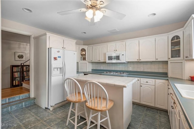2691 Rocklyn Rd, Shaker Heights, OH 44122 - kitchen with white appliances, glass insert cabinets, a kitchen island, ceiling fan, and decorative backsplash