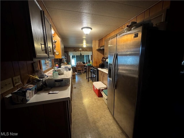 1110 3rd St, Belpre, OH 45714 - kitchen with stainless steel electric range oven, light countertops, wood walls, fridge with ice dispenser, and under cabinet range hood