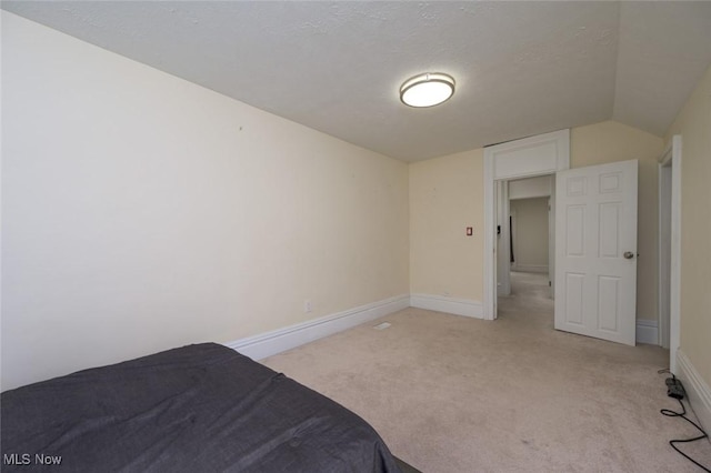 bedroom with baseboards, light carpet, and lofted ceiling