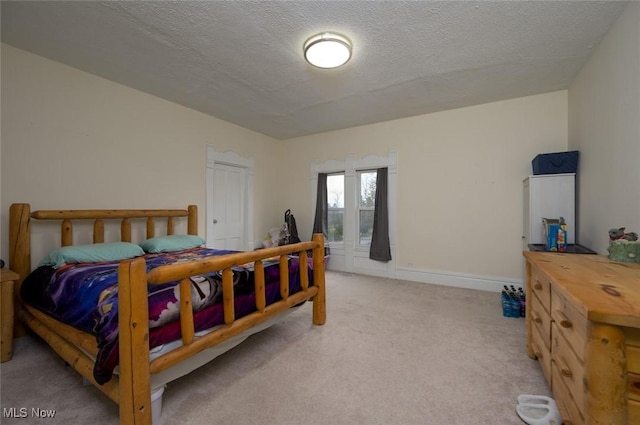 bedroom with a textured ceiling and light colored carpet