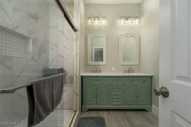 full bath featuring double vanity, a marble finish shower, and a sink