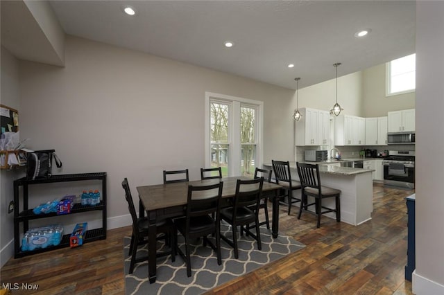 dining room featuring a high ceiling, dark wood-style flooring, and recessed lighting