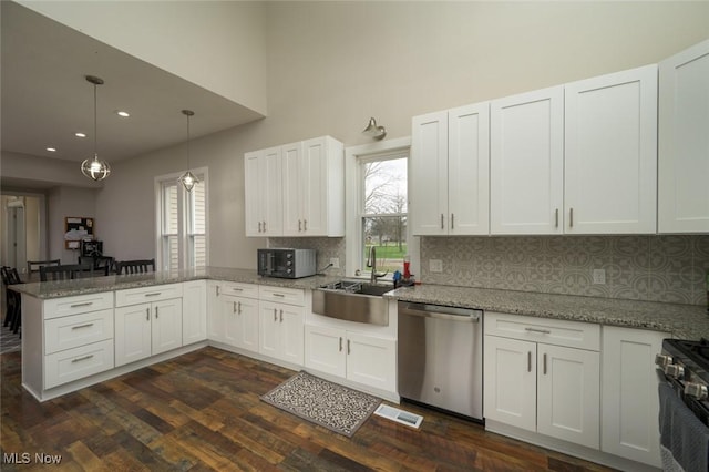 kitchen featuring visible vents, a sink, a peninsula, stainless steel appliances, and backsplash