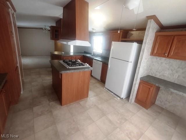 kitchen featuring white appliances, a sink, dark countertops, brown cabinets, and island range hood