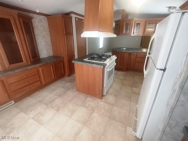 kitchen featuring white appliances, glass insert cabinets, brown cabinetry, dark countertops, and premium range hood