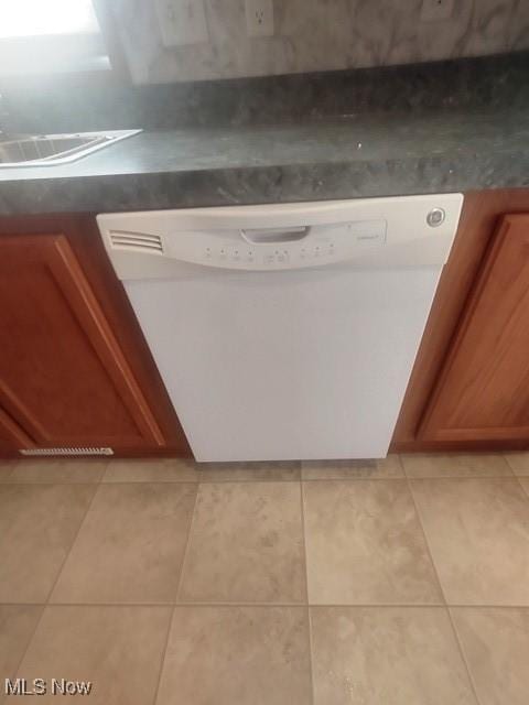 interior details featuring white dishwasher, brown cabinets, and dark countertops