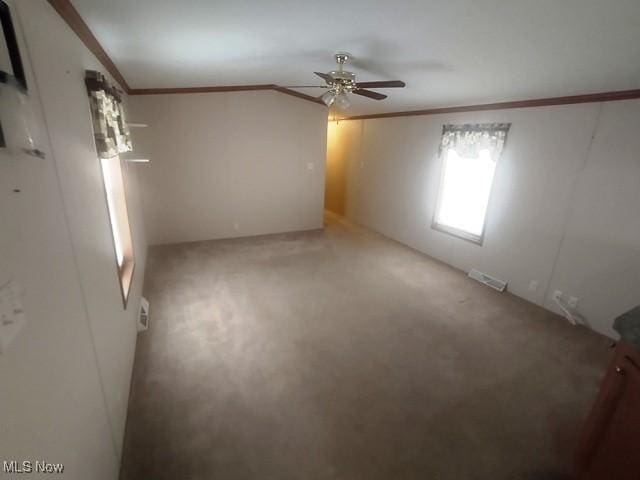 carpeted empty room featuring ceiling fan, ornamental molding, and visible vents