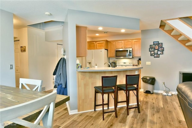 345 S Linden Ct, Warren, OH 44484 - kitchen featuring light countertops, a kitchen breakfast bar, white appliances, a peninsula, and light wood-style floors