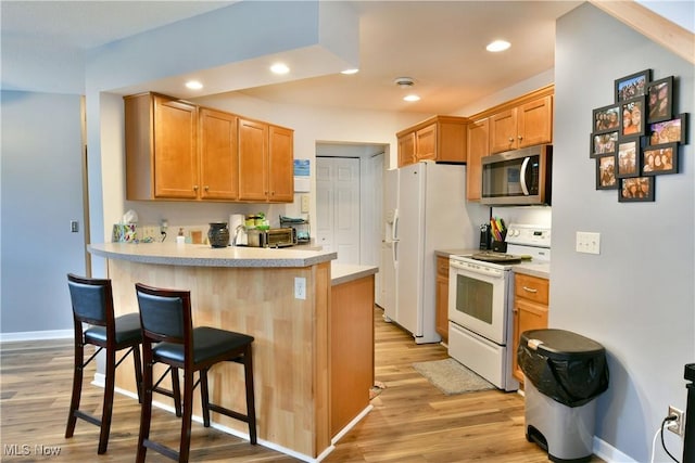 345 S Linden Ct, Warren, OH 44484 - kitchen featuring white appliances, a kitchen breakfast bar, light wood-style flooring, recessed lighting, and light countertops