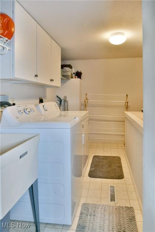 345 S Linden Ct, Warren, OH 44484 - clothes washing area featuring visible vents, baseboards, light tile patterned floors, separate washer and dryer, and cabinet space