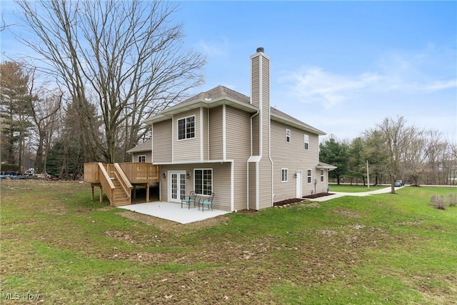 rear view of house with a deck, a patio area, a yard, a chimney, and stairway