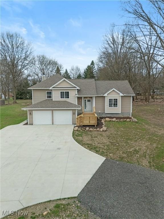 split level home featuring an attached garage, roof with shingles, driveway, and a front yard