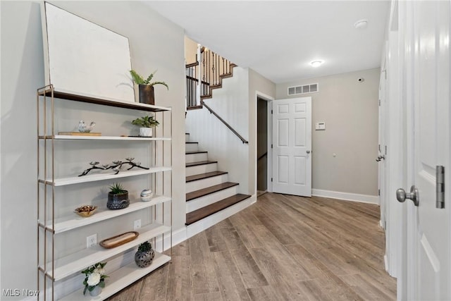 entrance foyer with visible vents, baseboards, stairway, and wood finished floors