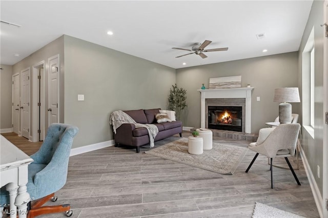 living area featuring wood finished floors, ceiling fan, baseboards, and visible vents
