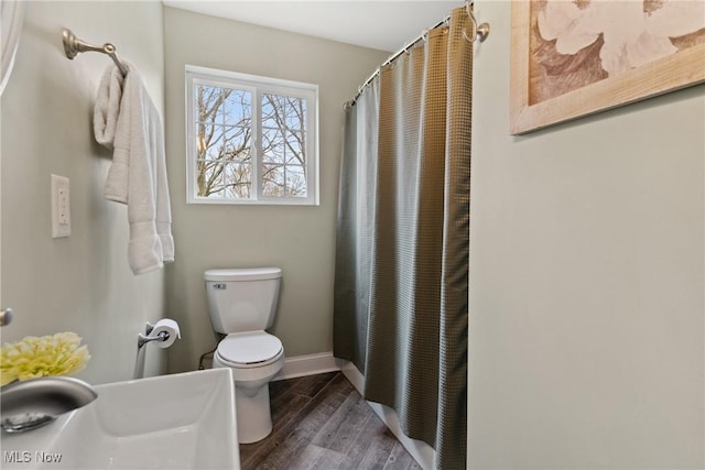 bathroom featuring baseboards, a shower with curtain, a sink, toilet, and wood finished floors