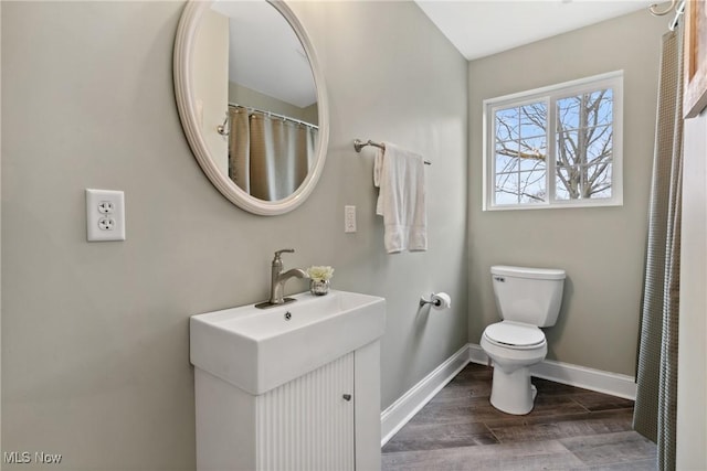full bath with toilet, wood finished floors, vanity, and baseboards
