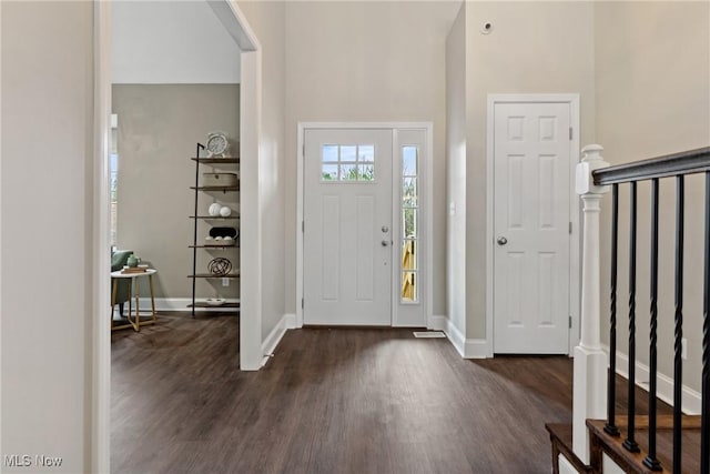 entrance foyer with dark wood-type flooring, a high ceiling, baseboards, and stairway