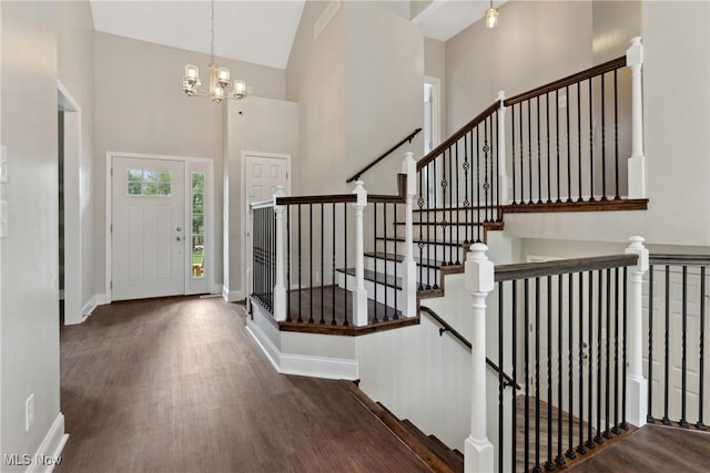 foyer entrance with baseboards, an inviting chandelier, a high ceiling, and wood finished floors