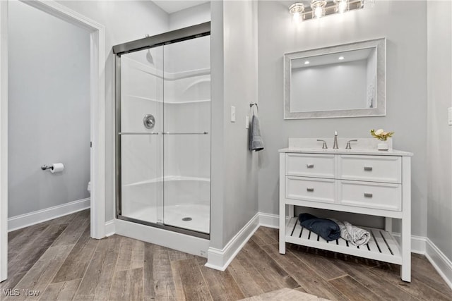bathroom with a shower stall, wood finished floors, vanity, and baseboards