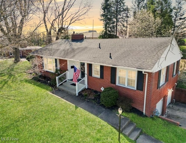 ranch-style house featuring a chimney, a shingled roof, a front lawn, and brick siding