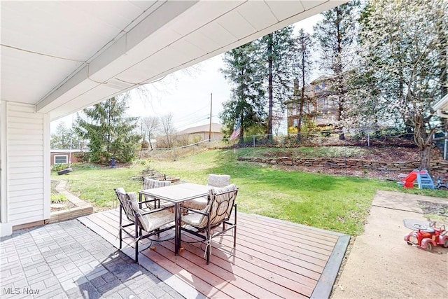 wooden deck with outdoor dining area, fence, and a lawn
