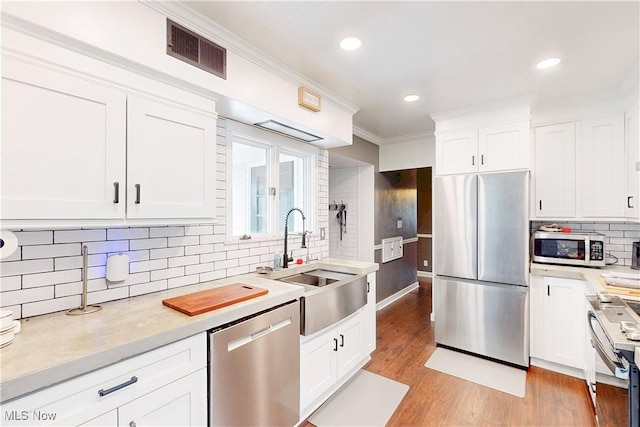 kitchen featuring visible vents, light countertops, a sink, stainless steel appliances, and decorative backsplash