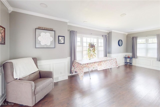 sitting room featuring a decorative wall, wainscoting, dark wood-style flooring, and crown molding