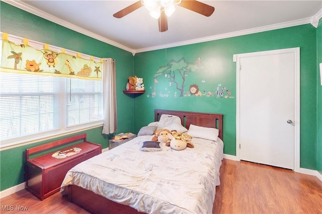 bedroom with baseboards, crown molding, a ceiling fan, and wood finished floors