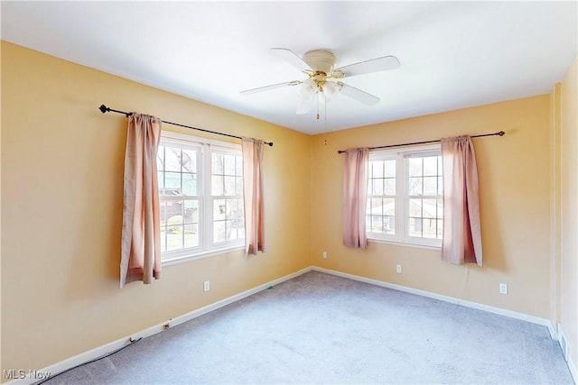 carpeted empty room featuring baseboards and a ceiling fan