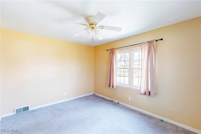 empty room with carpet, visible vents, baseboards, and a ceiling fan
