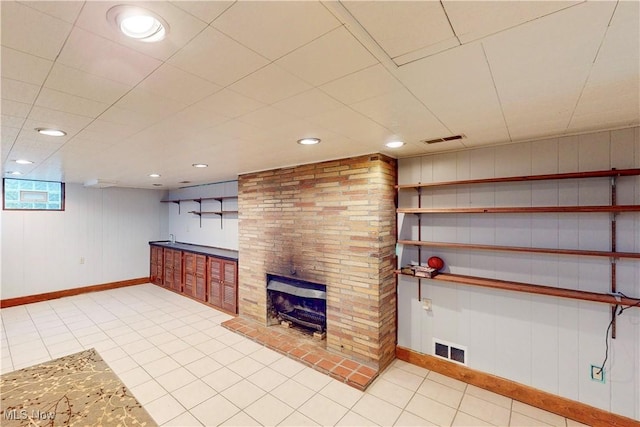 below grade area featuring tile patterned floors, a fireplace, baseboards, and visible vents