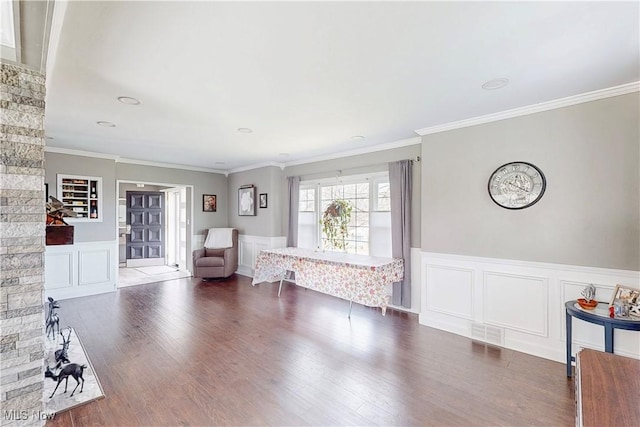 sitting room with a decorative wall, wainscoting, and wood finished floors