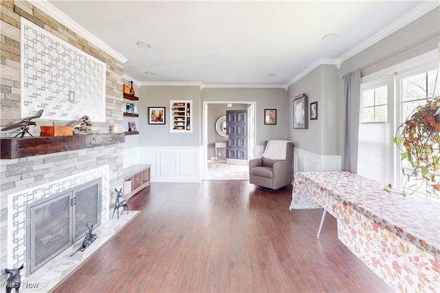 interior space with a fireplace, ornamental molding, a wainscoted wall, and wood finished floors