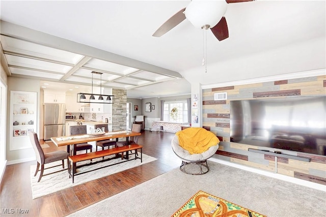living area featuring coffered ceiling, wood finished floors, a ceiling fan, and visible vents
