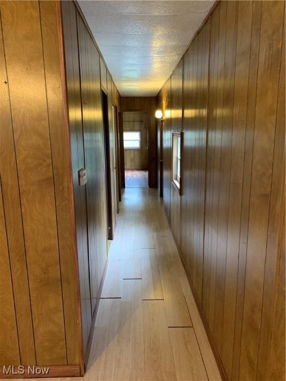 hallway with wooden walls and light wood-type flooring