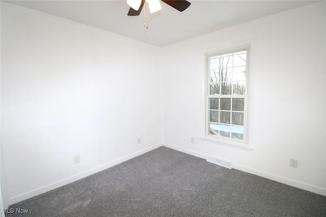 spare room featuring dark carpet, visible vents, baseboards, and a ceiling fan