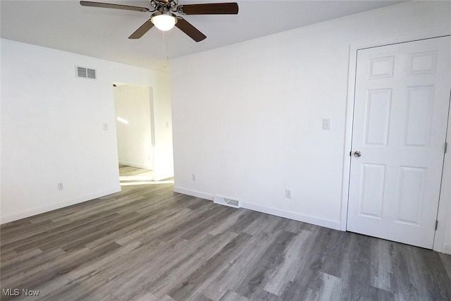 empty room with visible vents, ceiling fan, wood finished floors, and baseboards
