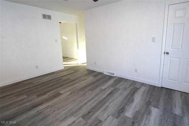 empty room featuring visible vents, ceiling fan, baseboards, and dark wood finished floors