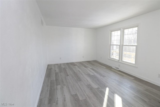 spare room featuring visible vents, baseboards, and light wood-type flooring