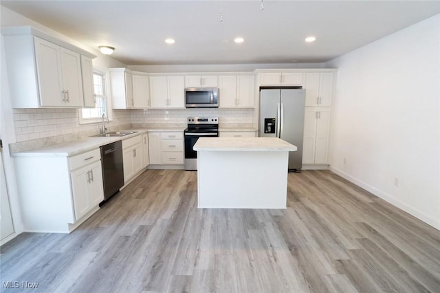 kitchen featuring tasteful backsplash, a center island, light wood-style floors, stainless steel appliances, and a sink