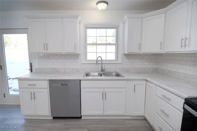 kitchen featuring light wood finished floors, stainless steel dishwasher, a sink, and white cabinets