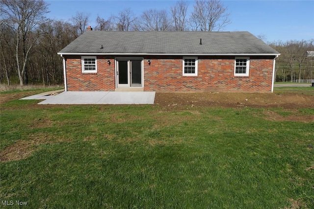 rear view of house featuring a patio, brick siding, and a yard