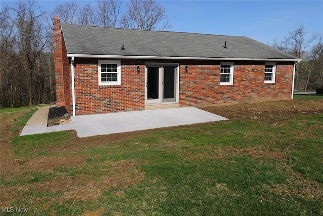 back of property with a patio area, brick siding, a lawn, and a chimney