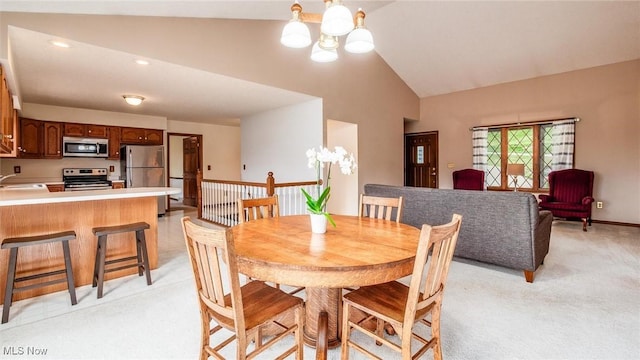 dining space with high vaulted ceiling, light carpet, and a chandelier
