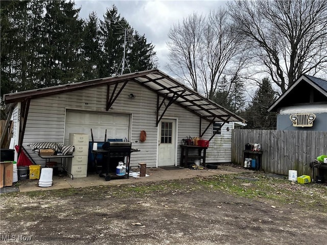 view of outbuilding featuring an outdoor structure, fence, and dirt driveway