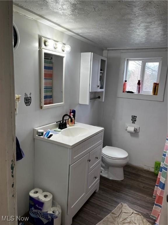 full bathroom with toilet, a textured ceiling, wood finished floors, and vanity