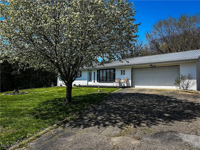 3265 Tieber Rd, Stockport, OH 43787 - ranch-style house featuring aphalt driveway, metal roof, a front lawn, brick siding, and an attached garage