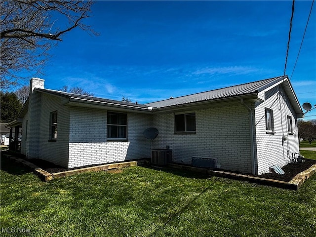 3265 Tieber Rd, Stockport, OH 43787 - rear view of house with central AC, a yard, metal roof, brick siding, and a chimney