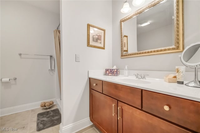 bathroom with a shower, vanity, and baseboards