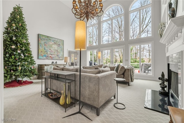 carpeted living room featuring a chandelier, a high ceiling, and a fireplace